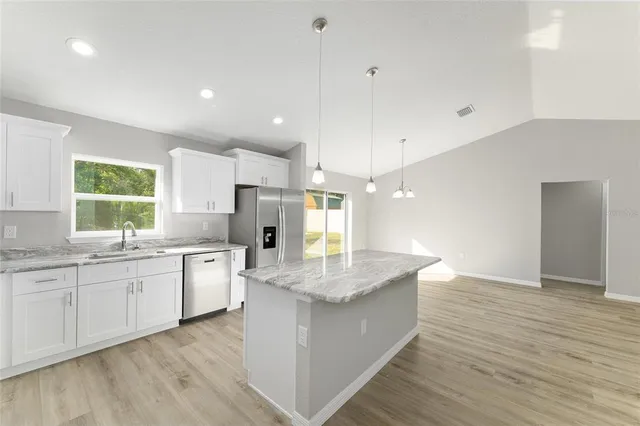 a large kitchen with granite countertop a sink and a stove top oven