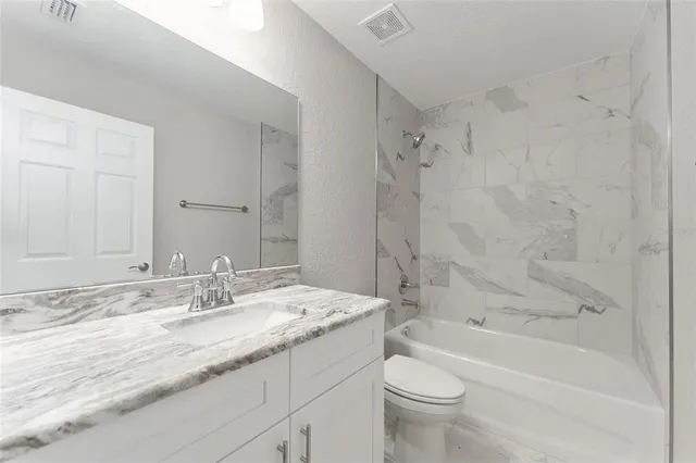 a bathroom with a granite countertop sink a toilet and a bathtub