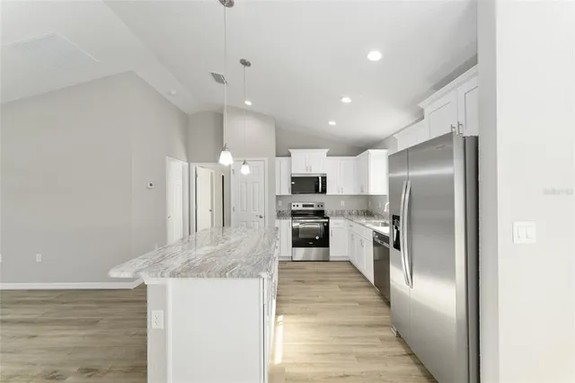 a kitchen with stainless steel appliances granite countertop a refrigerator and a stove top oven