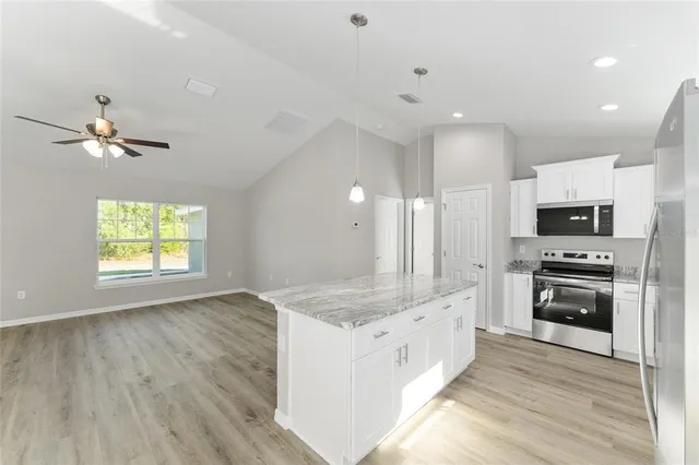 a large white kitchen with a large window a sink and stainless steel appliances
