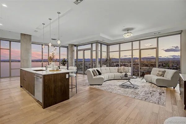 a living room with furniture large windows and wooden floor