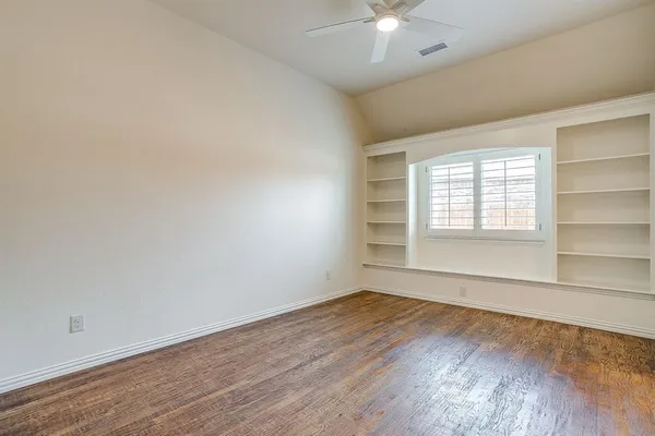an empty room with wooden floor and window