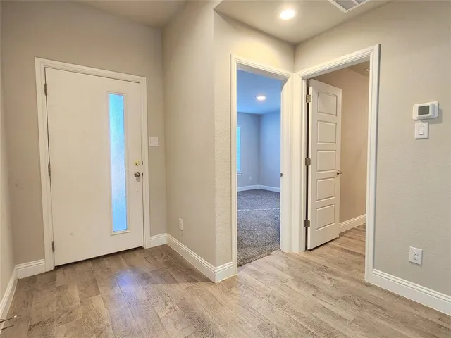 a view of a hallway with wooden floor and a bathroom