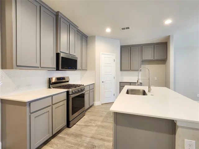 a kitchen with kitchen island granite countertop a sink a stove a refrigerator cabinets and a counter top space