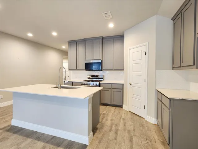 a view of kitchen with kitchen island microwave and cabinets