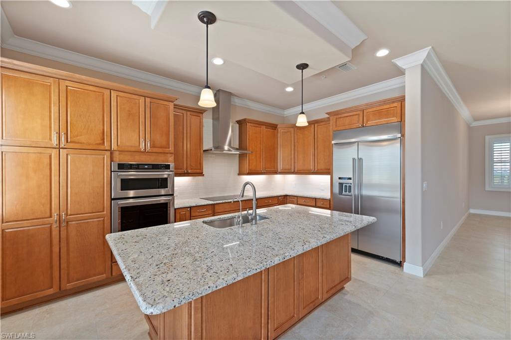 a kitchen with stainless steel appliances granite countertop a sink a refrigerator and a stove top oven