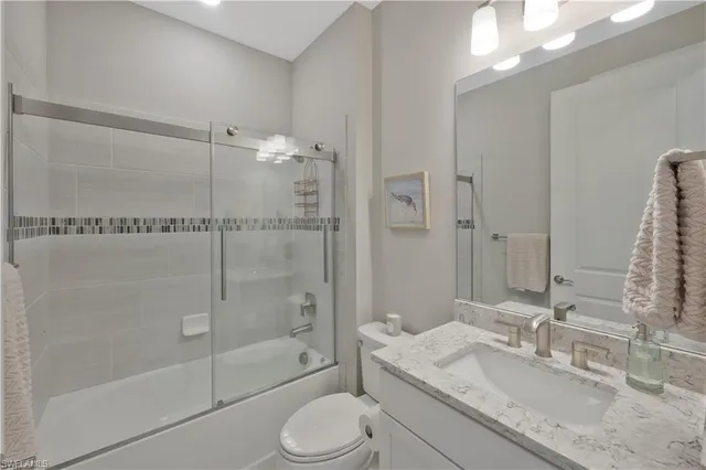 a bathroom with a granite countertop sink toilet mirror and shower