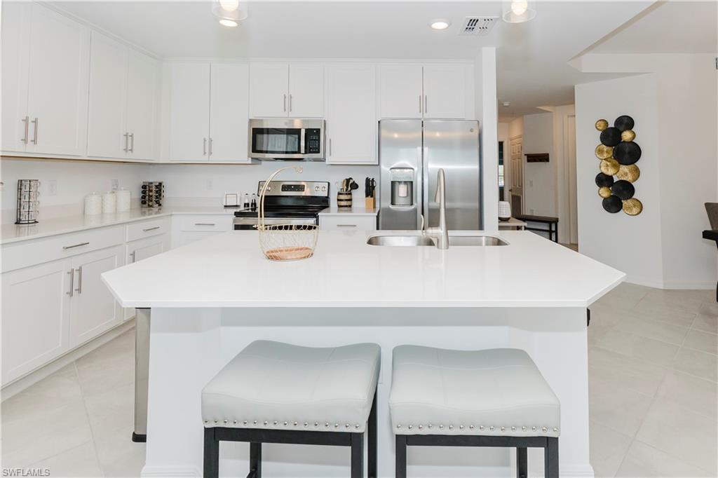 43993 Boardwalk Loop, Unit 1928 Babcock Ranch, FL 33982 - Photo 12 of 50 a kitchen with stainless steel appliances a refrigerator sink microwave and cabinets