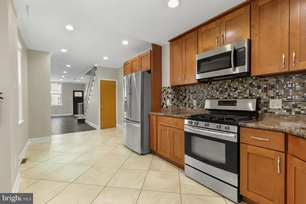 a kitchen with stainless steel appliances granite countertop a stove microwave and refrigerator
