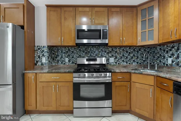 a kitchen with granite countertop a stove top oven microwave and cabinets