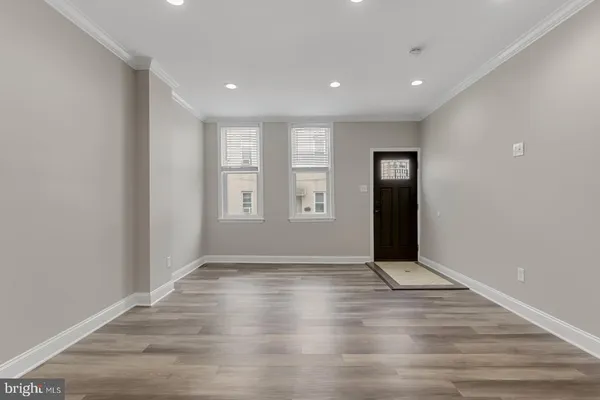 an empty room with wooden floor and natural light