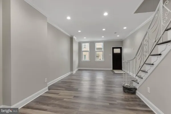 a view of an empty room with wooden floor and stairs