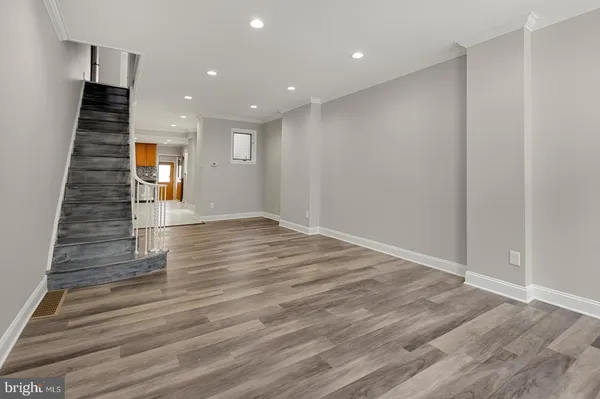 an empty room with wooden floor & staircase