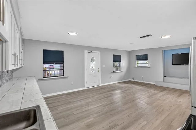 a view of an empty room with window and wooden floor