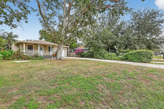 a view of house with yard and trees in the background