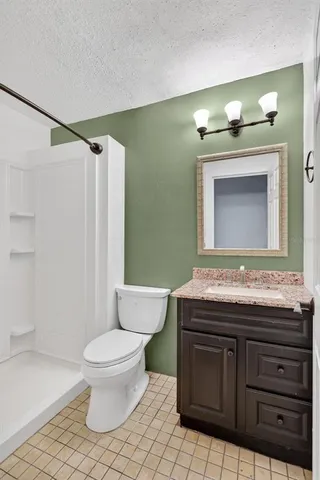 a bathroom with a granite countertop toilet a sink and a mirror