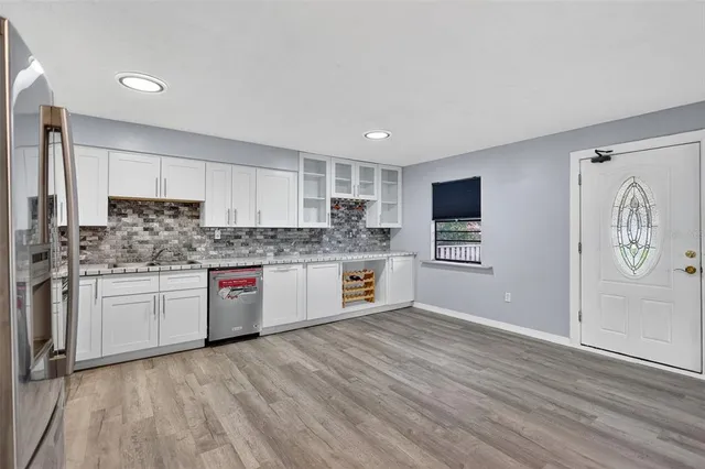 a large kitchen with stainless steel appliances granite countertop a stove a sink dishwasher and a refrigerator with wooden floor