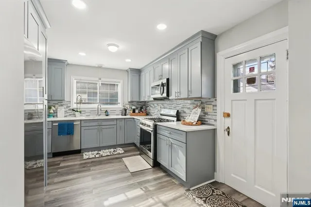 a kitchen with stainless steel appliances granite countertop a stove top oven a sink a refrigerator and cabinets
