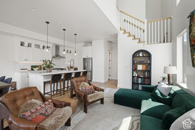 1141 520 West Midway, UT 84049 - Photo 6 of 40 Open-concept living area featuring a kitchen island with seating, white shaker cabinetry, stainless steel appliances, and a dual-height staircase with wood treads and white balusters
