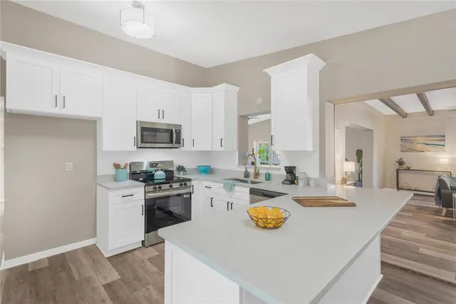 a view of a kitchen with a stove top oven a sink dishwasher a dining table and chairs with wooden floor