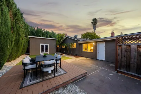 a view of a backyard with table and chairs potted plants and wooden fence