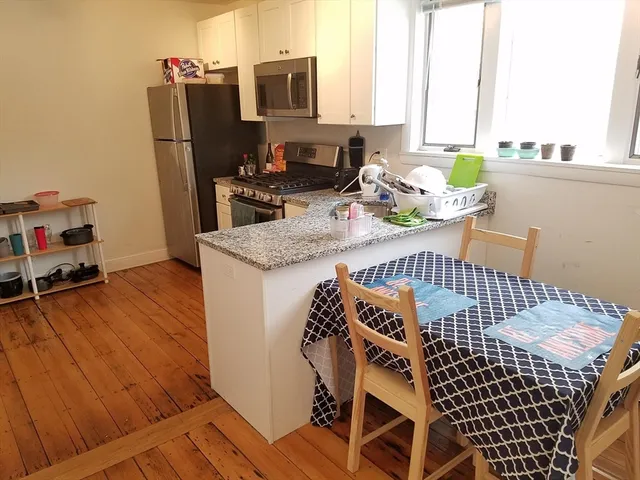 a kitchen with a stove a sink and wooden floor