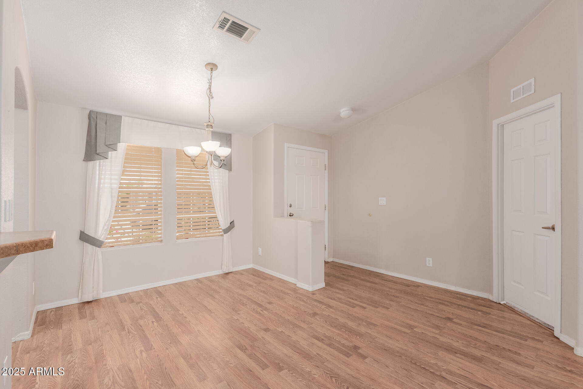 2550 South Ellsworth Road, Unit 366 Mesa, AZ 85209 - Photo 8 of 27 an empty room with wooden floor exposed radiator and windows