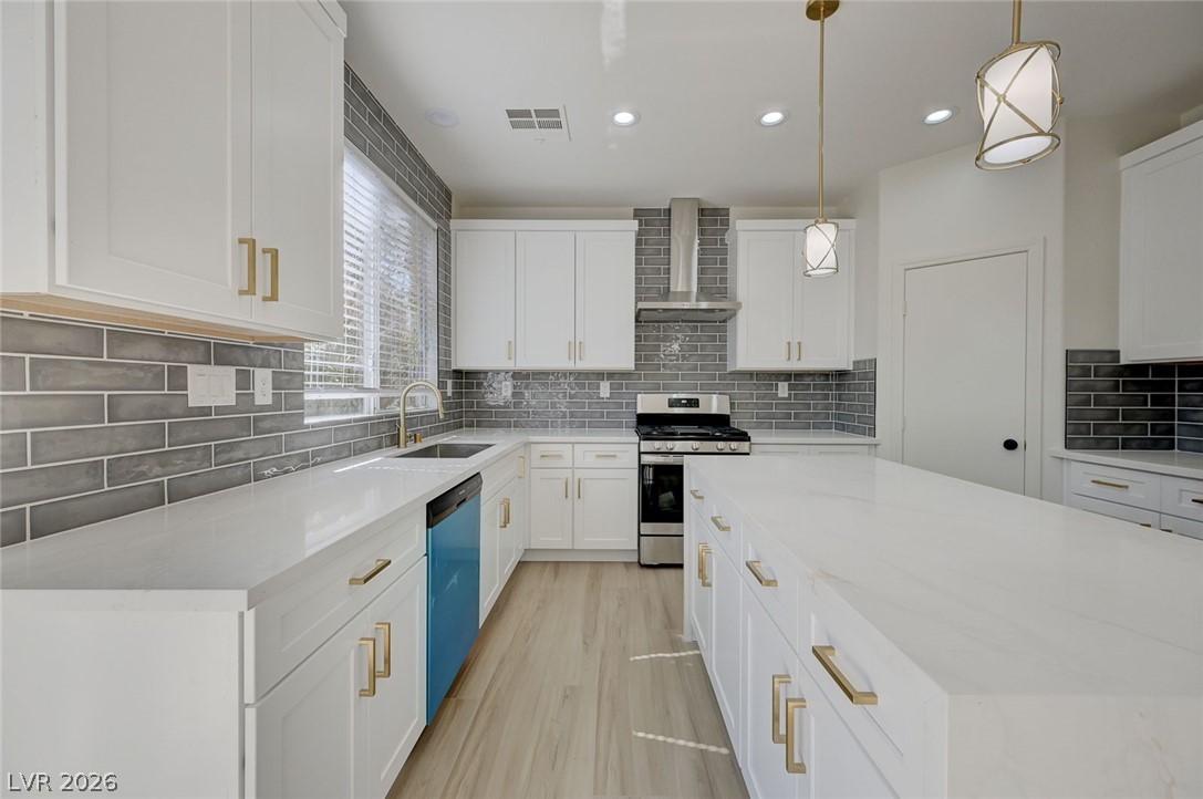 9687 Ridgebluff Avenue Las Vegas, NV 89148 - Photo 11 of 57 Kitchen with light stone countertops, stainless steel gas stove, white cabinetry, dishwasher, and hanging light fixtures