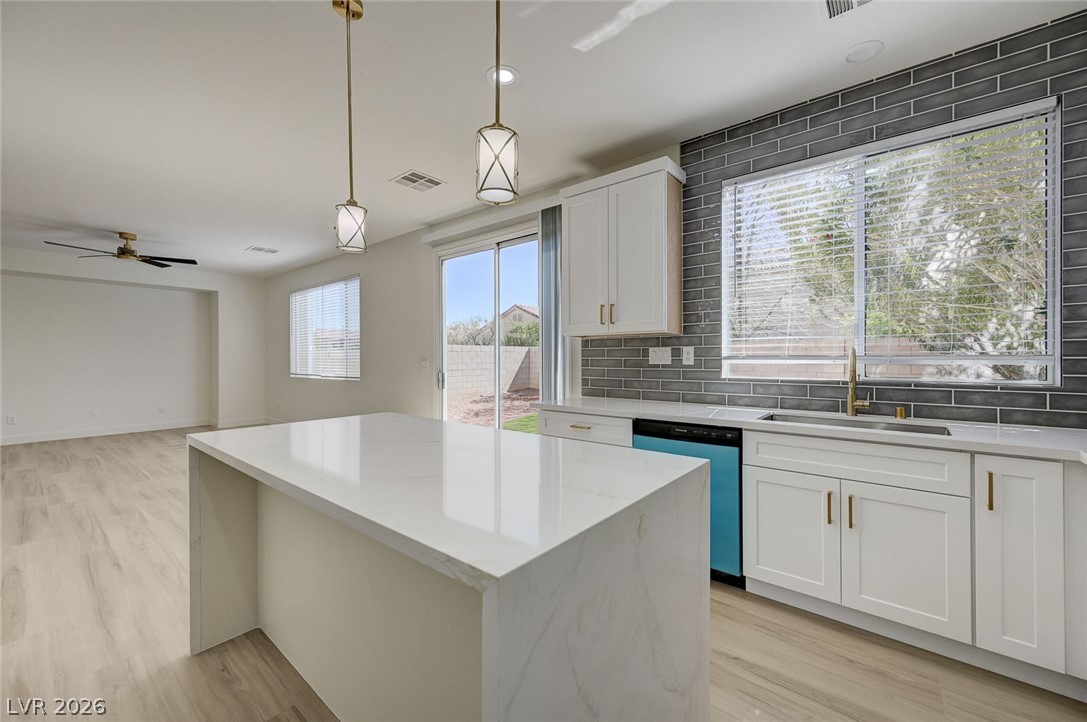 9687 Ridgebluff Avenue Las Vegas, NV 89148 - Photo 57 of 57 Kitchen featuring decorative light fixtures, a kitchen island, open floor plan, tasteful backsplash, and dishwasher