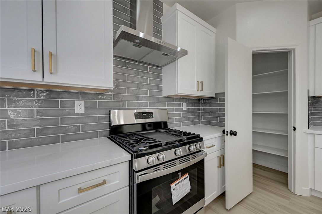 9687 Ridgebluff Avenue Las Vegas, NV 89148 - Photo 15 of 57 Kitchen with gas range, range hood, tasteful backsplash, and white cabinets