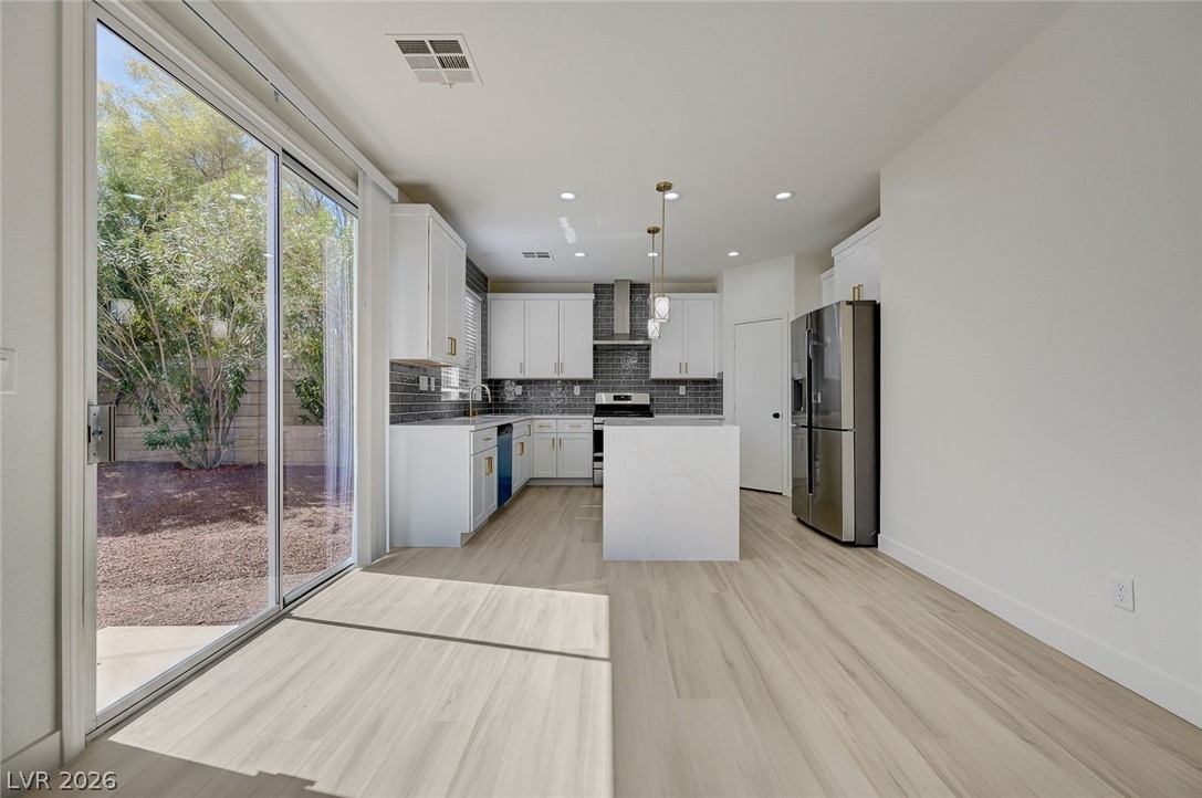 9687 Ridgebluff Avenue Las Vegas, NV 89148 - Photo 16 of 57 Kitchen with stainless steel appliances, white cabinets, decorative light fixtures, a kitchen island, and backsplash