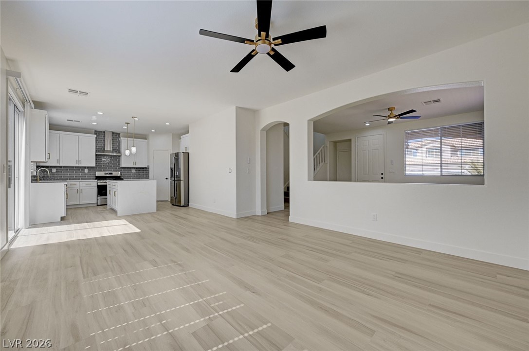 9687 Ridgebluff Avenue Las Vegas, NV 89148 - Photo 17 of 57 Unfurnished living room featuring a ceiling fan, arched walkways, and light wood finished floors