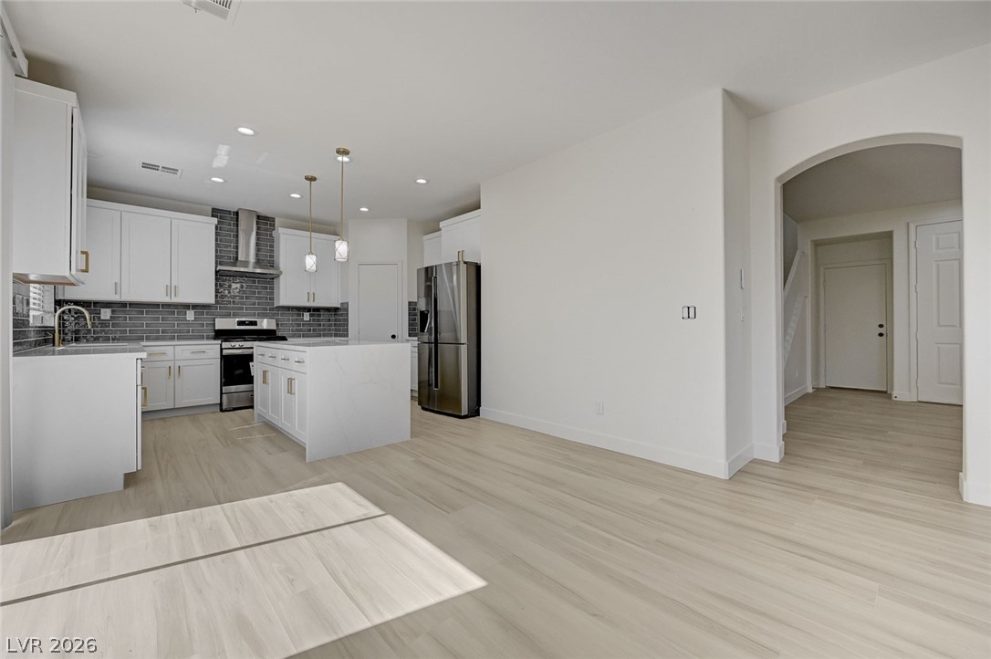 9687 Ridgebluff Avenue Las Vegas, NV 89148 - Photo 18 of 57 Kitchen with arched walkways, a kitchen island, stainless steel appliances, and white cabinets
