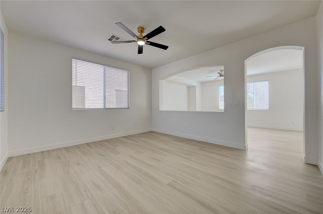 9687 Ridgebluff Avenue Las Vegas, NV 89148 - Photo 19 of 57 Spare room featuring ceiling fan, light wood-style flooring, and arched walkways