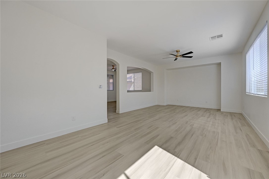 9687 Ridgebluff Avenue Las Vegas, NV 89148 - Photo 23 of 57 Spare room featuring arched walkways, light wood-type flooring, a ceiling fan, and healthy amount of natural light
