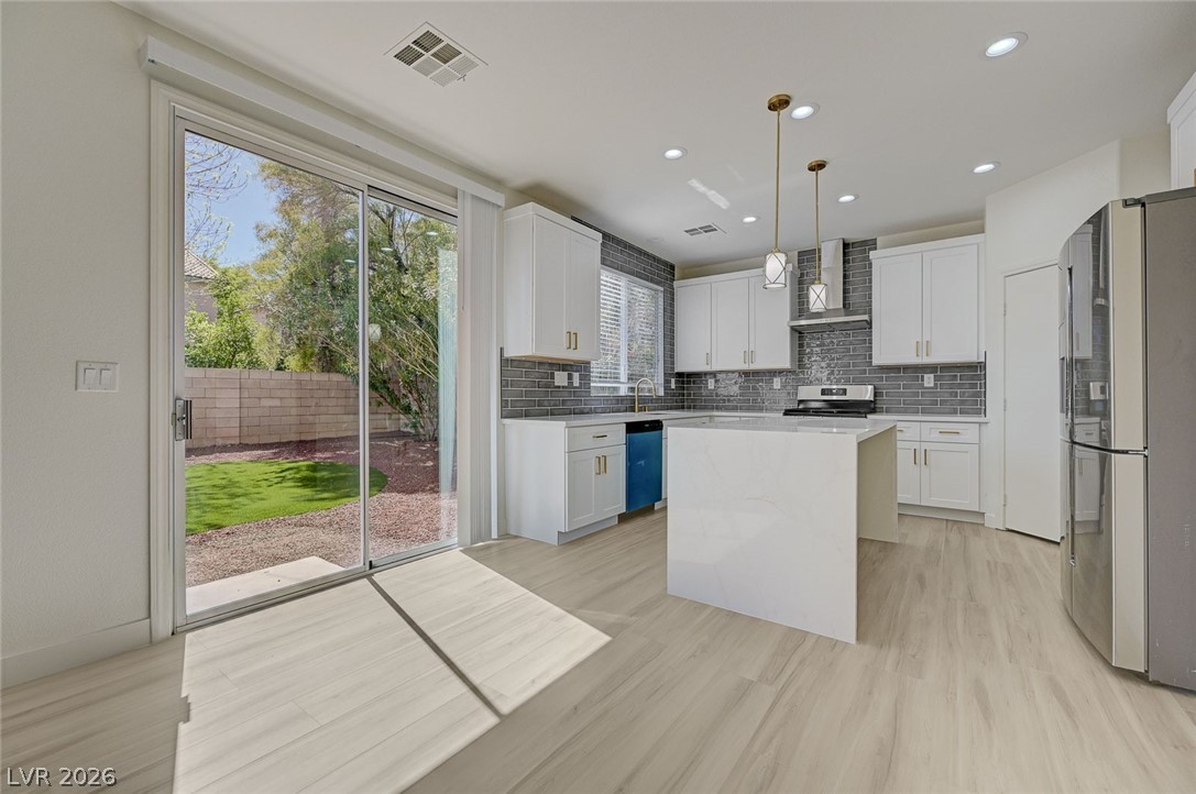 9687 Ridgebluff Avenue Las Vegas, NV 89148 - Photo 10 of 57 Kitchen featuring stainless steel appliances, a kitchen island, light stone counters, and white cabinetry