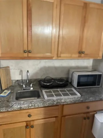 a kitchen with granite countertop a sink a stove and cabinets