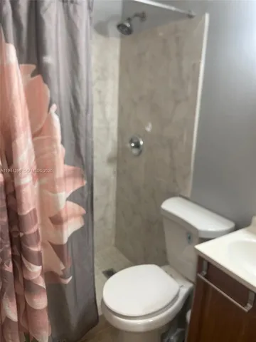 a white toilet sitting next to a shower curtain