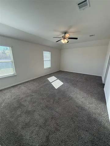 an empty room with windows and fan