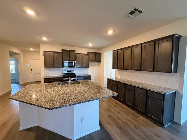 a kitchen with stainless steel appliances granite countertop a sink stove and refrigerator