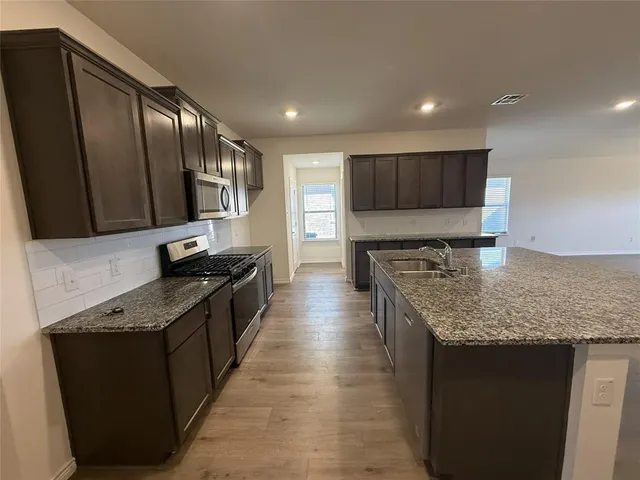 a kitchen with stainless steel appliances granite countertop a sink a stove and a refrigerator