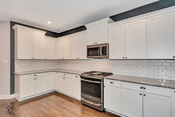 a kitchen with granite countertop white cabinets stainless steel appliances and a sink