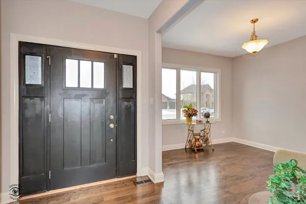 a view of a hallway with wooden floor and a dining room