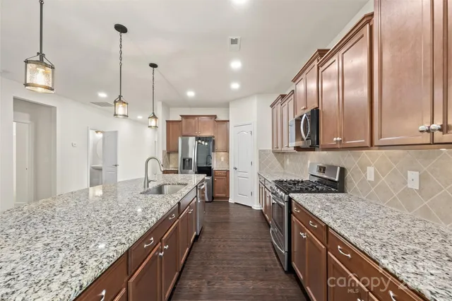 a kitchen with stainless steel appliances granite countertop a stove and a microwave