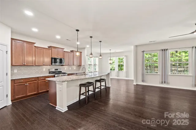 a kitchen with stainless steel appliances granite countertop a refrigerator a sink and a stove