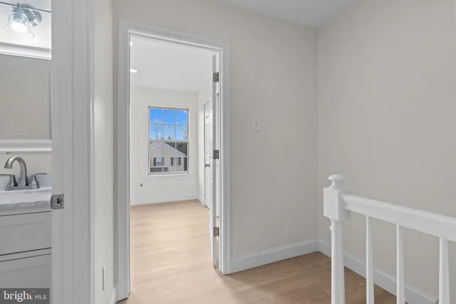 a view of a hallway with wooden floor and a bathroom