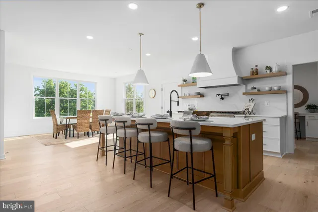 a kitchen with stainless steel appliances kitchen island granite countertop a stove a sink a dining table and chairs