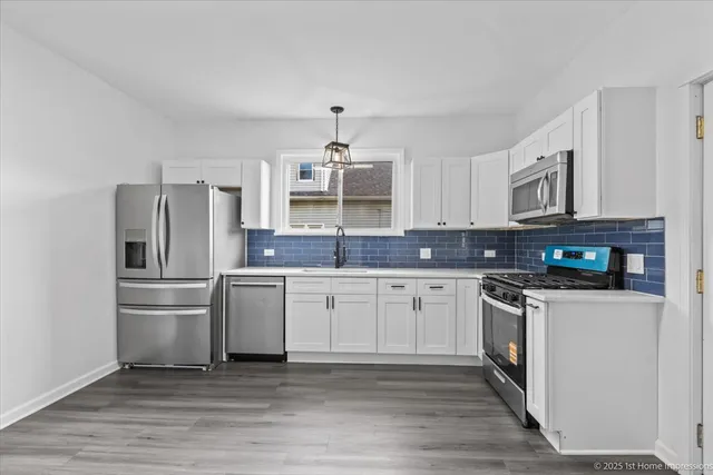 a kitchen with stainless steel appliances granite countertop a stove top oven a refrigerator and white cabinets