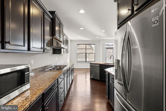 a kitchen with stainless steel appliances granite countertop a refrigerator a stove and a wooden floors