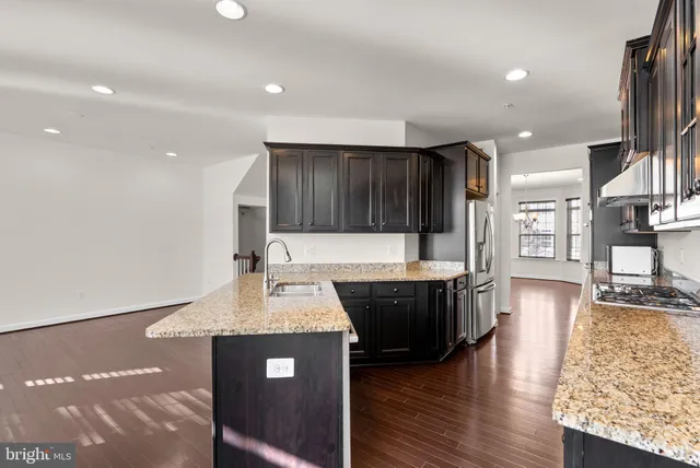 a kitchen with stainless steel appliances granite countertop a sink a stove and a wooden floors
